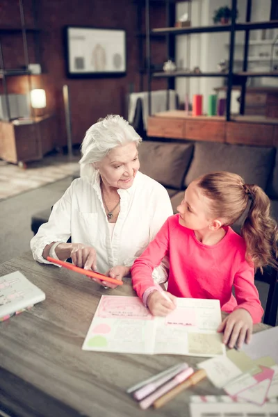 Hilfreiche Oma hilft ihrer Enkelin bei den Hausaufgaben — Stockfoto