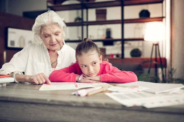 Girl sitting near her granny while doing homework together — Stock Photo, Image