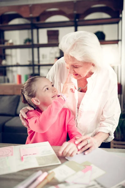 Girl wearing pink shirt touching nose of her loving granny — Stock Photo, Image