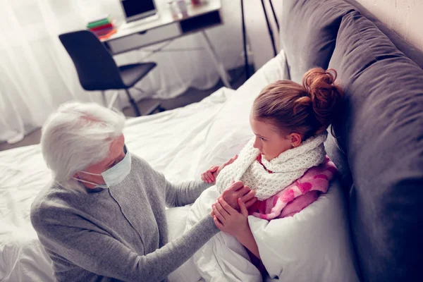 Девушка страдает от гриппа, держа за руки свою поддерживающую бабушку — стоковое фото