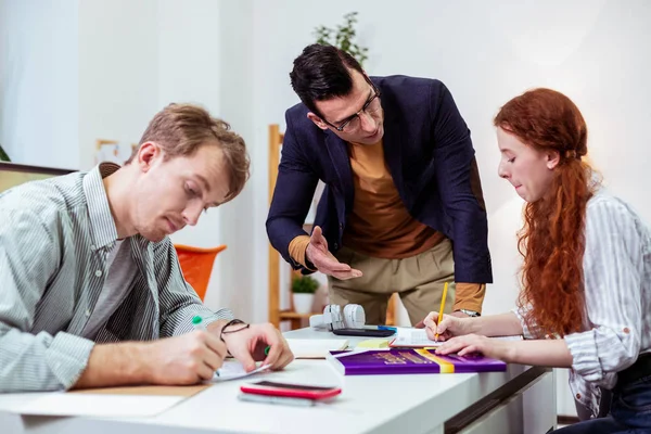 Buen estudiante trabajador tomando notas después de que el profesor — Foto de Stock