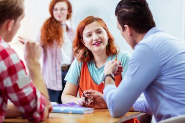 Pozitif kızıl saçlı kadın meslektaşlarına gülümseyen