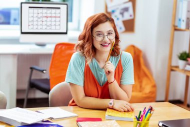 Mutlu kırmızı saçlı kadın kalemini tutan