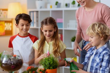 Üç öğrenci botanik öğretmeni ile bitkileri sulama