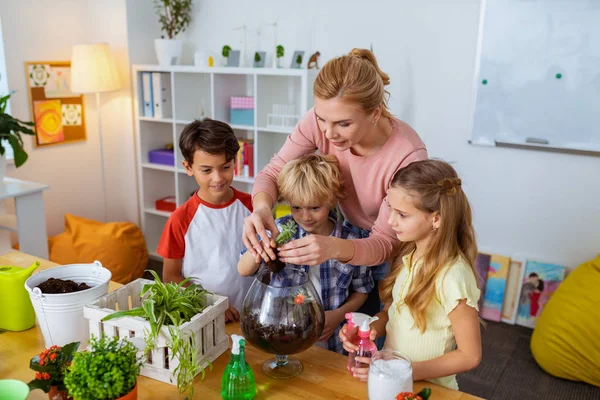 Hilfreiche Botaniklehrerin lehrt ihre Schüler, sich um Pflanzen zu kümmern — Stockfoto