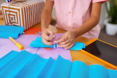 Mevcut kutu için kağıt yay hazırlanıyor pembe gömlek giyen çocuk