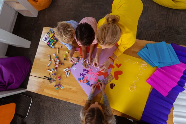 Insegnante e alunni utilizzando carta a colori per fare ritagli — Foto Stock