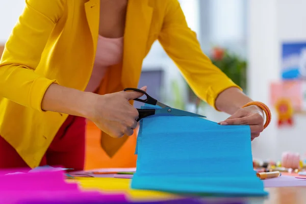 Teacher wearing yellow jacket cutting blue paper for her pupils — Stock Photo, Image