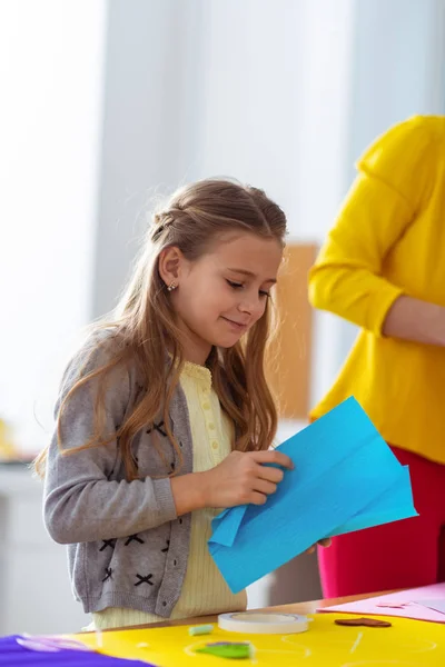 Söt Schoolgirl innehar blått papper för tillämpad prydnad — Stockfoto