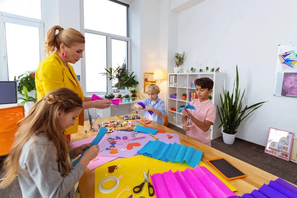 Blondhaarige Lehrerin unterstützt ihre Schüler bei der Herstellung von angewandten Ornamenten — Stockfoto