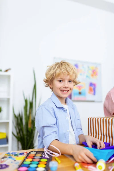 Blonde dark-eyed schoolboy feeling excited after nice art lesson — Stock Photo, Image