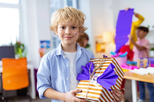 Blonde school jongen toont grote huidige doos na het versieren van het — Stockfoto