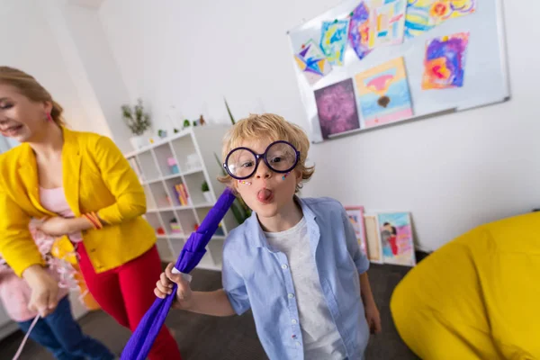 Funny boy in massive glasses showing tongue after cool lesson — Stock Photo, Image