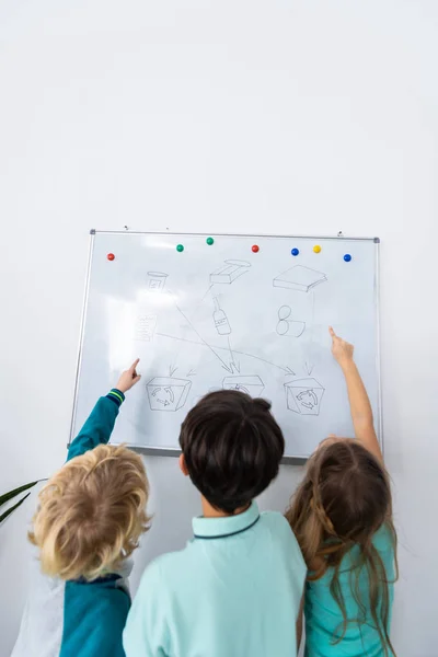 Pojken står mellan sina klasskamrater nära whiteboard — Stockfoto