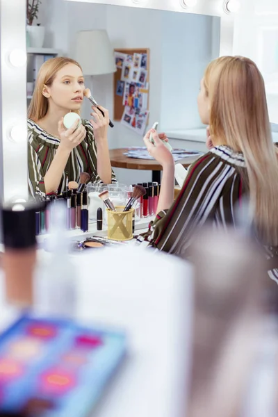 Aangename jonge vrouw kijkt naar zichzelf in de spiegel — Stockfoto