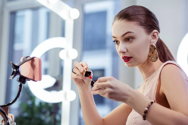 Schöne glückliche Frau zeigt einen glänzenden Lippenstift — Stockfoto