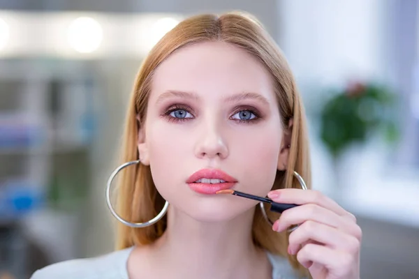 Retrato de una bonita mujer atractiva que aplica lápiz labial rosa — Foto de Stock