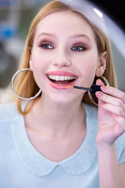 Nice young woman using a shiny lipgloss — Stock Photo, Image