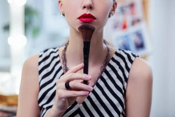 Güzel iyi görünümlü kadın bir makyaj fırçası ile çenesine dokunmadan — Stok fotoğraf