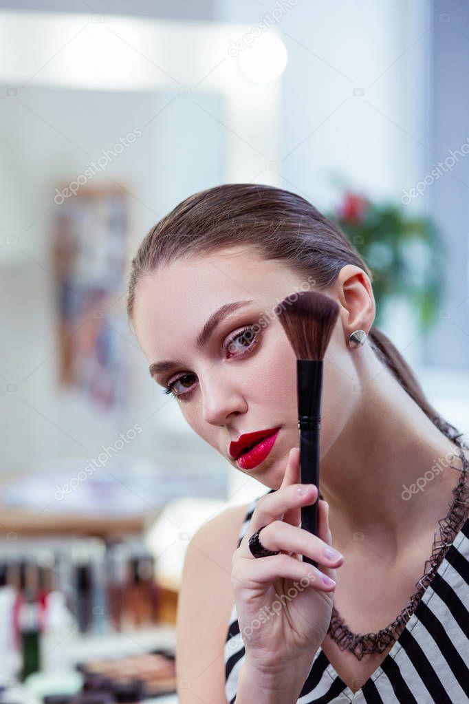 Nice young woman standing with a powder brush