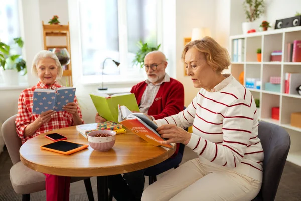 Nice aged people sitting with books at home