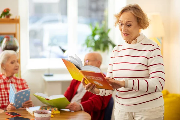 Pozitív idős nő olvas egy könyvet asztrológia — Stock Fotó