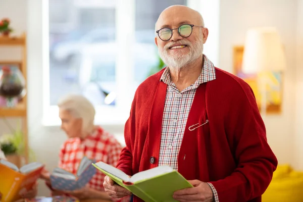 Радостный пожилой мужчина, стоящий с книгой — стоковое фото