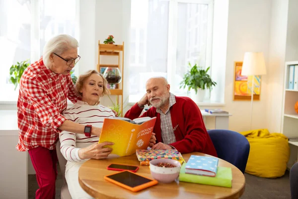 Piacevole donna anziana che indica il libro — Foto Stock