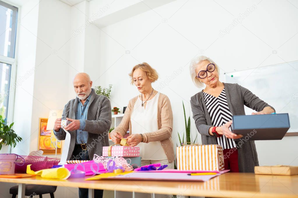 Pleasant elderly people looking at their gifts