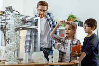 Turuncu tablet taşıyan ve el kaldıran aktif sarışın öğrenci