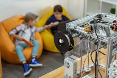 Küçük çocuklar laboratuvarda otururken sandalye çantalarında öğretmen bekliyor