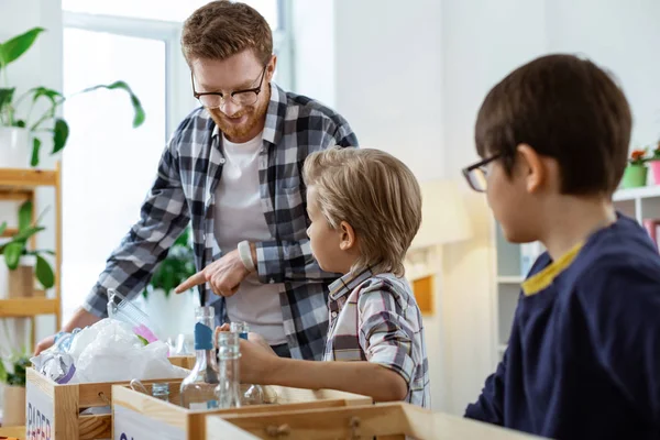 Ijverig brunette jongen in heldere glazen opstijgen bekers van glazen flessen — Stockfoto