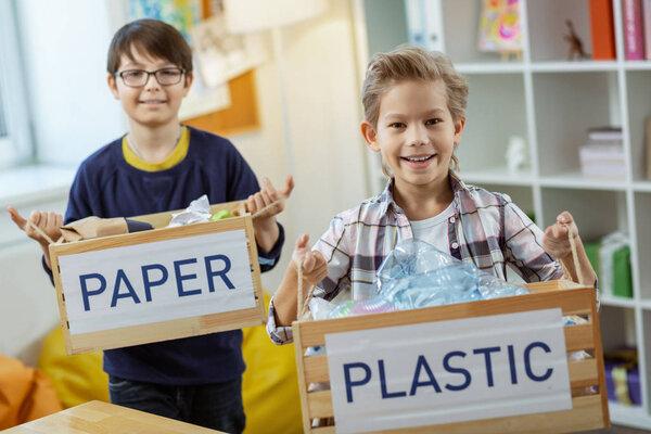 Happy diligent kids displaying mindful consumption while holding boxes