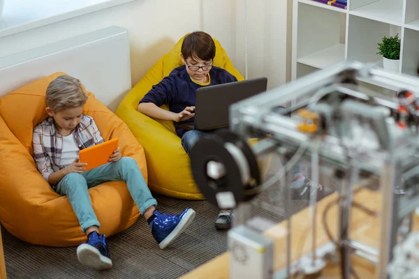 Concentrated little boys comfortably sitting in bright chairs bags — Stock Photo, Image