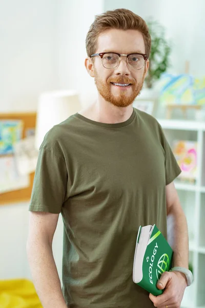 Attentive ginger man in clear glasses wearing green t-shirt