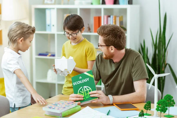 Leende mörkhåriga pojke inspekterande plast hus under lektionen — Stockfoto