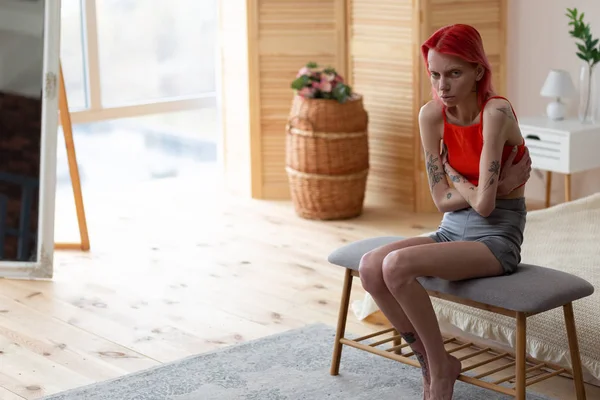 Red-haired anorexic woman sitting in bedroom near the window — Stock Photo, Image