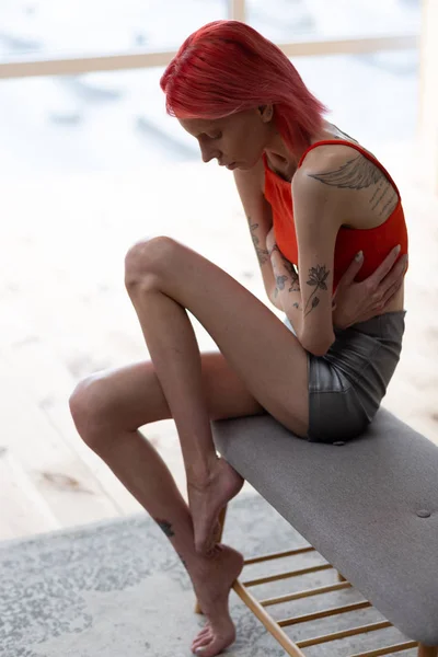 Mujer anoréxica pelirroja con tatuajes con dolor de estómago — Foto de Stock