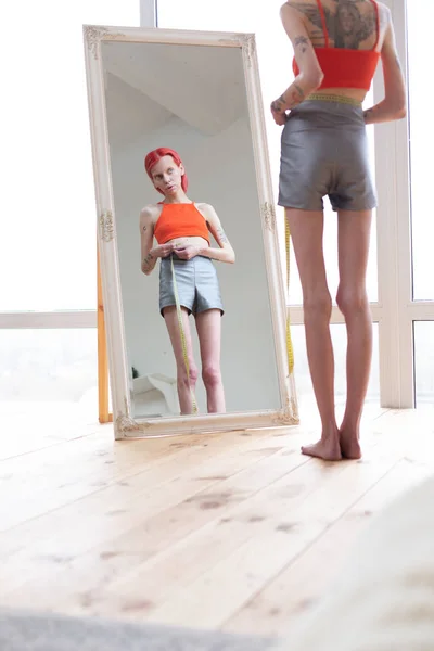 Nesmírně hubená a štíhlá anorexická žena, která hledí do zrcadla — Stock fotografie