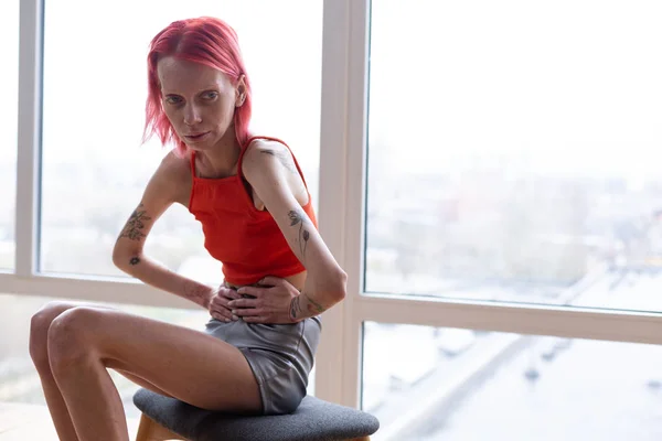 Mujer con anorexia sentada cerca de la ventana sintiéndose horrible — Foto de Stock