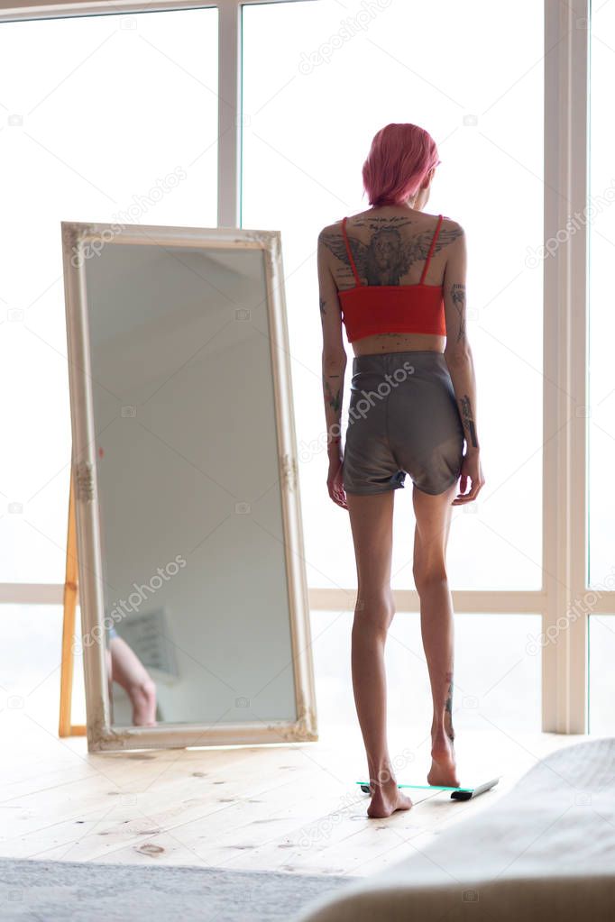 Skinny anorexic woman standing on weight scales near the mirror