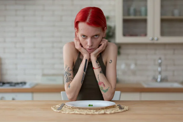 Mulher magro que sofre de anorexia sentado na cozinha — Fotografia de Stock