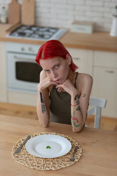 Woman with anorexia sitting in the kitchen feeling bad