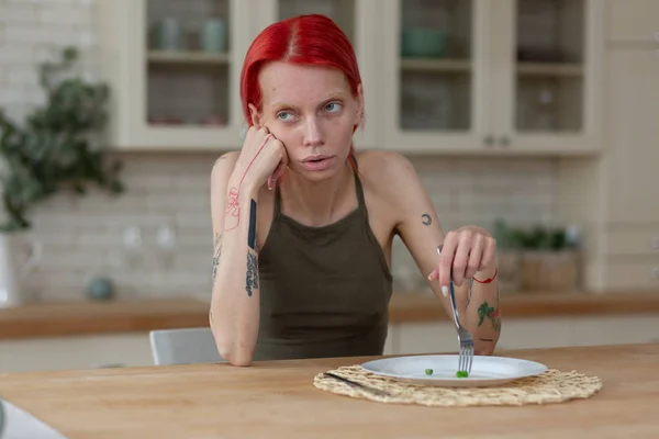 Mulher magra com bulimia comendo apenas três ervilhas verdes — Fotografia de Stock