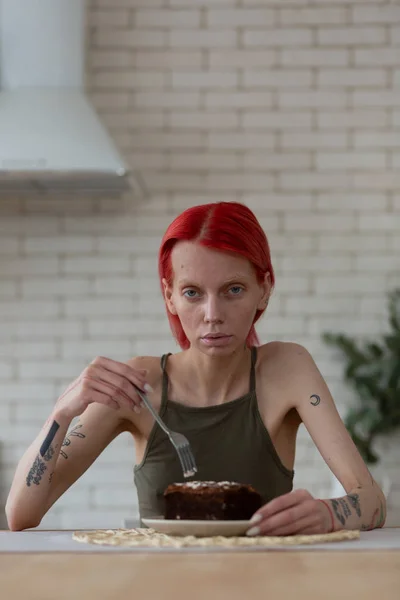 Mujer que sufre de anorexia sentada cerca de pastel de chocolate — Foto de Stock