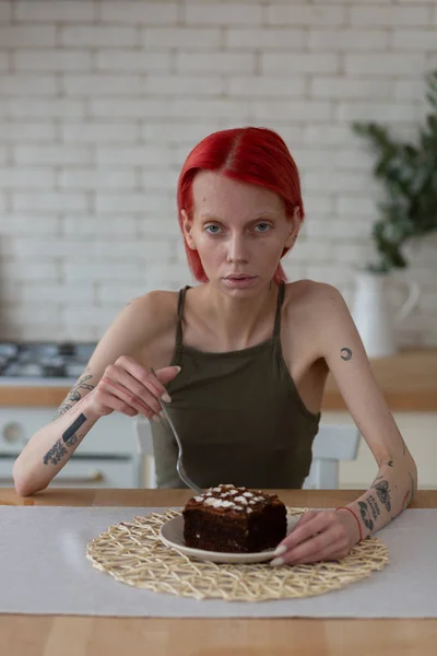 Extremely skinny woman thinking about eating chocolate cake