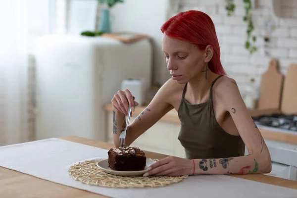 Anorexic woman looking at big piece of chocolate cake