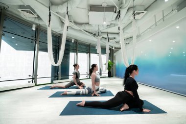 Kadınlar ve erkekler yoga yaparken bacaklarını esnetiyorlar.