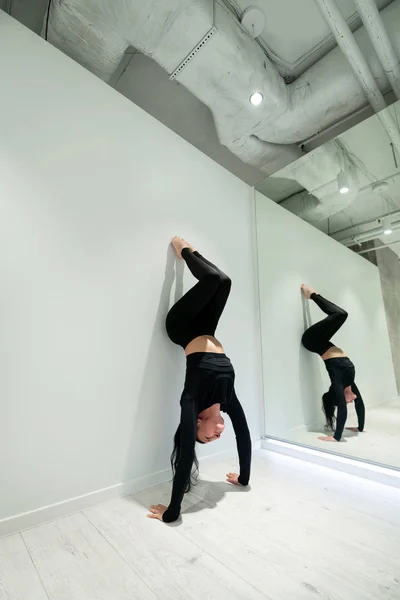 鏡の近くに腕を練習する黒髪のアクティブヨガトレーナー — ストック写真