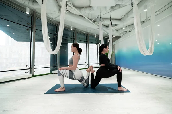 Women in leggings doing yoga together in spacious room